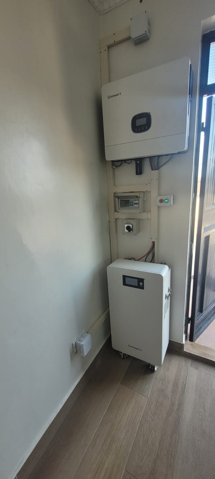 Growatt hybrid inverter above a protection box and floor-standing battery